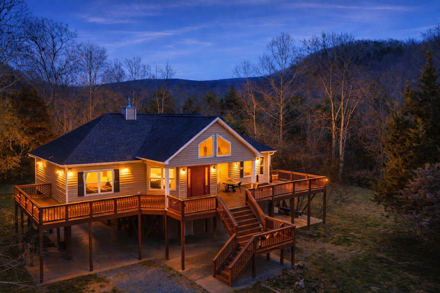A two-story wooden cabin with a deck and a staircase leading to a second level.