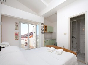 Habitación de hotel con cama, baño con ducha y balcón.