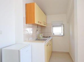 Cocina compacta con lavavajillas incorporado, una ventana pequeña y un refrigerador blanco.