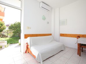 Un dormitorio con cama, una silla, aire acondicionado y vista a zonas verdes.