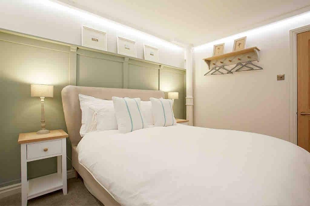 Un dormitorio con una cama grande, mesitas de noche y un estante en la pared con perchas.