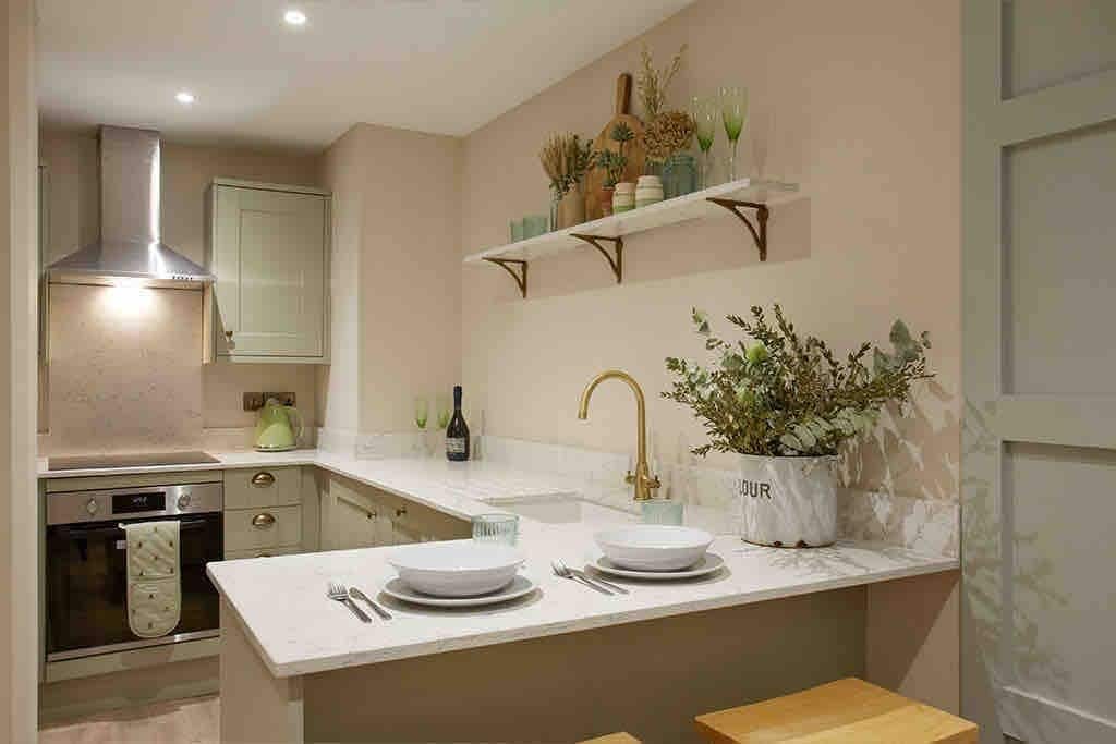 Una cocina moderna con una isla central, horno empotrado y campana extractora de acero inoxidable.