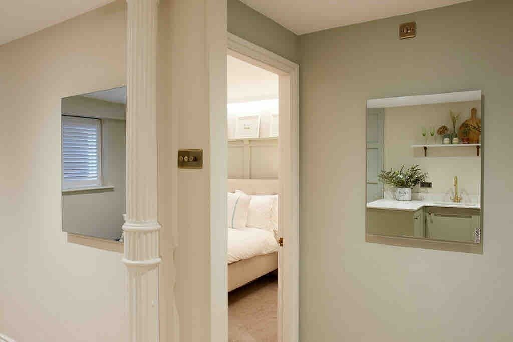 A bedroom with a bed, a window, and a bathroom with a mirror and shelves.