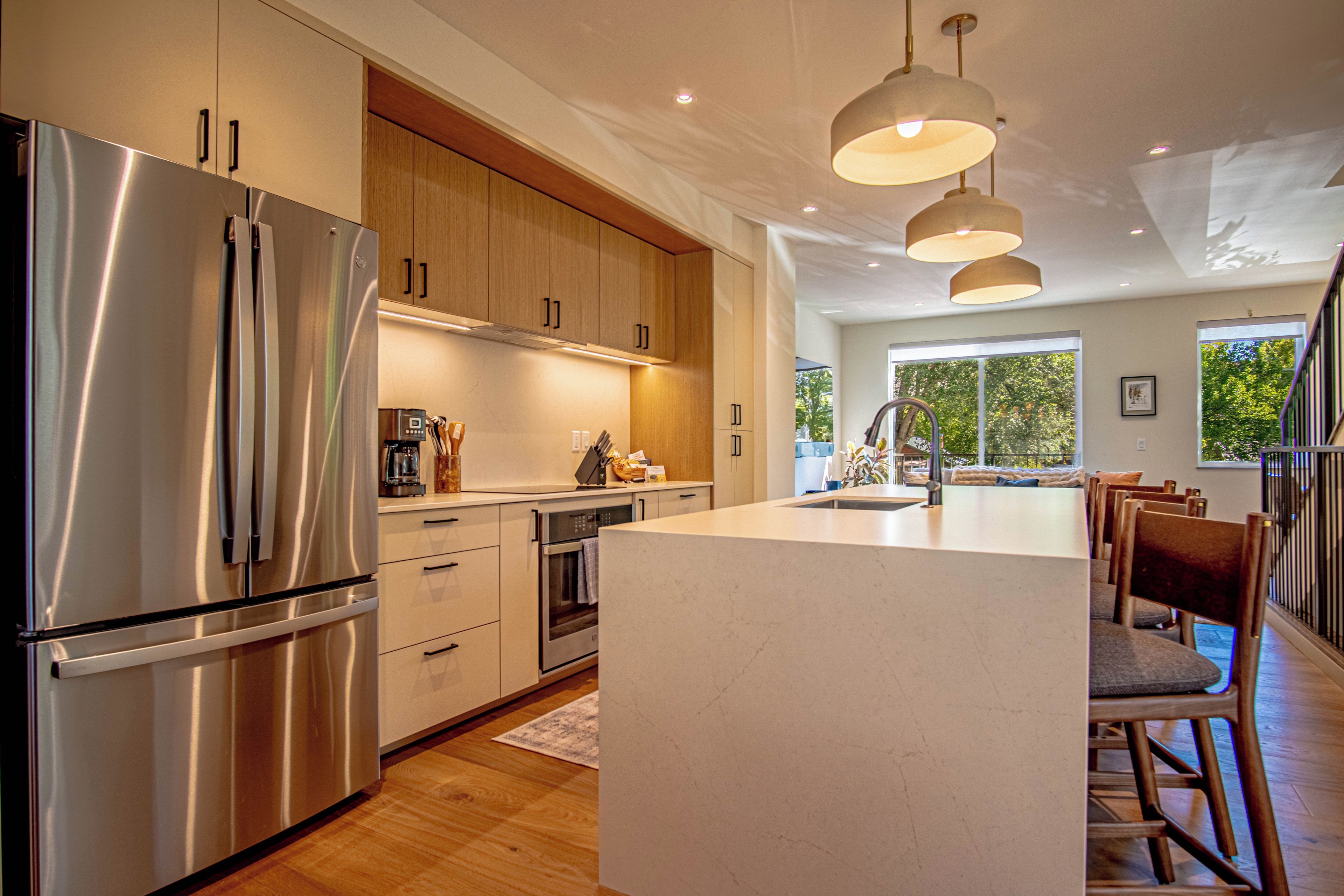 Una cocina moderna con electrodomésticos de acero inoxidable, armarios de madera e iluminación colgante.