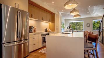 Una cocina moderna con electrodomésticos de acero inoxidable, armarios de madera e iluminación colgante.