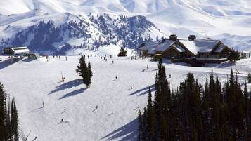 A ski resort with a lodge, ski slopes, and snow-covered mountains.
