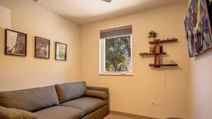 A living room with a sofa, a window, and wall-mounted shelves. - River Street Lookout - Lux 3BD w/ Rooftop Views + Hot tub - Downtown Hailey (Hailey)