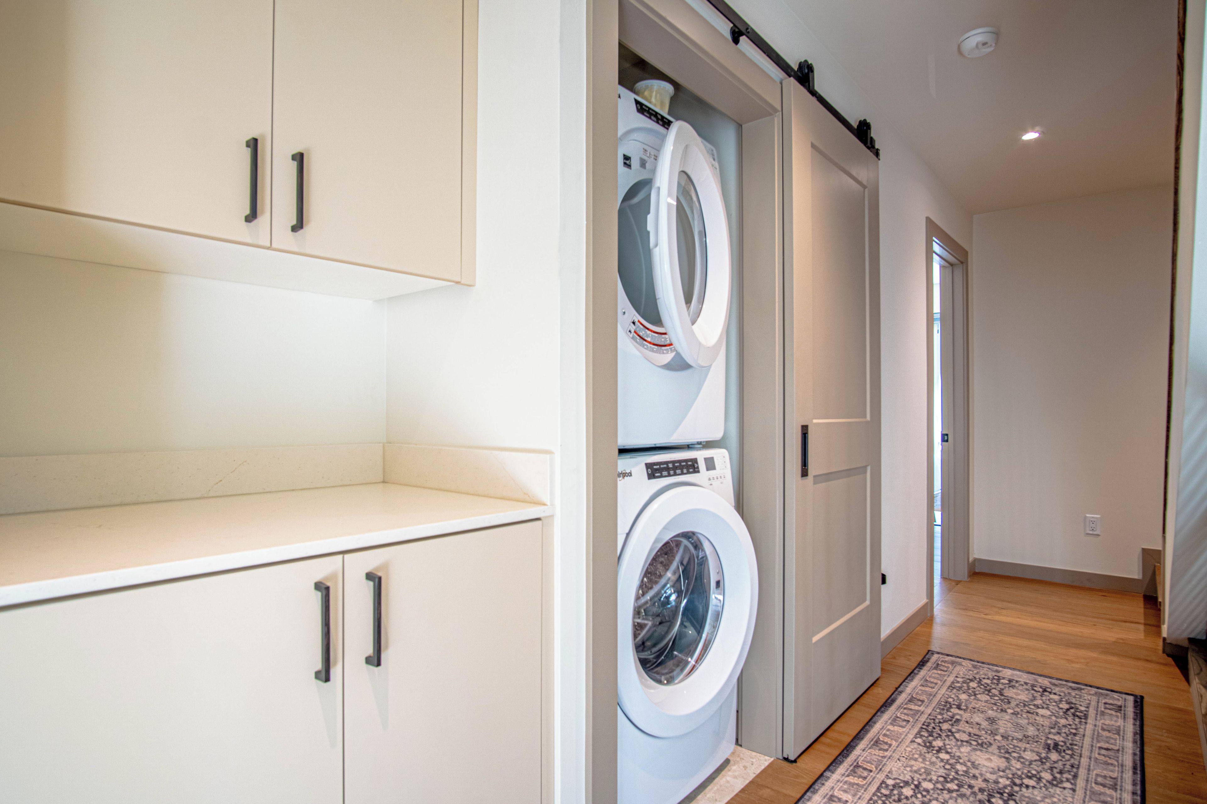 Une buanderie équipée d’un lave-linge et d’un sèche-linge, avec un plancher en bois et un tapis.