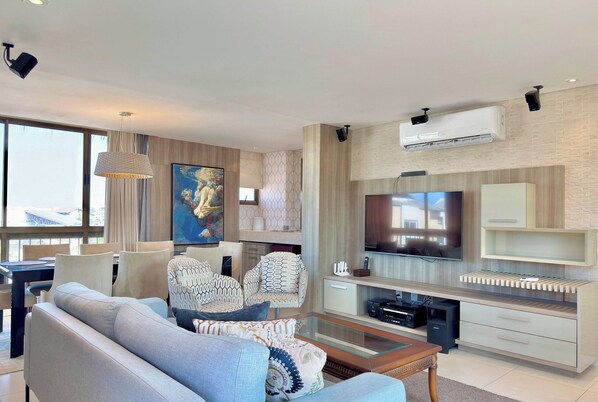 A modern living room with a sofa, a coffee table, a TV, and a painting. - Parque das Ilhas (Aquiraz)