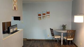 A room with a dining table, chairs, a small plant, and artwork on the walls.