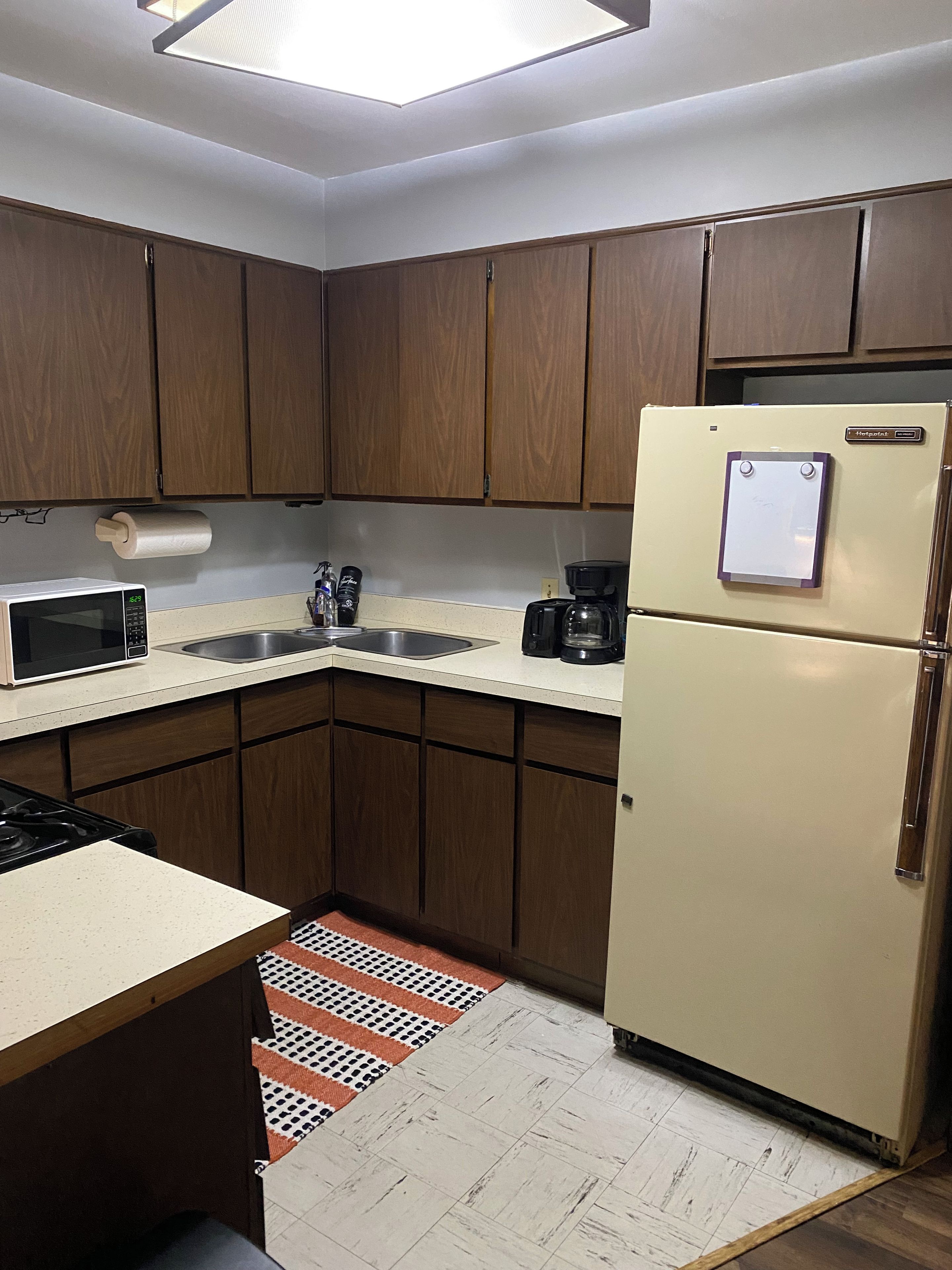 A kitchen with wooden cabinets, a microwave, a refrigerator, and a coffee maker.