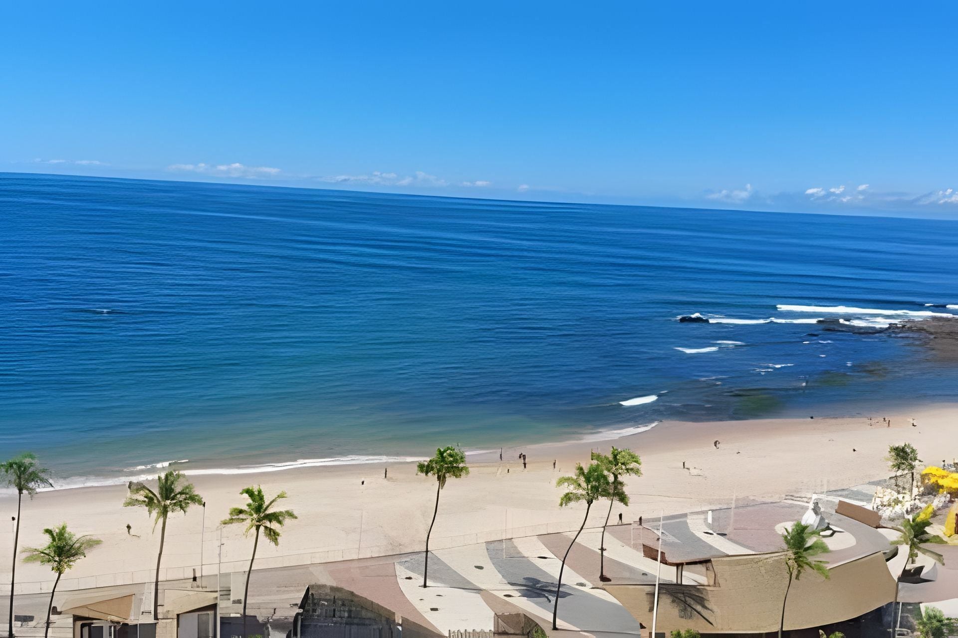 Uma praia com palmeiras, costa arenosa e oceano azul cristalino.