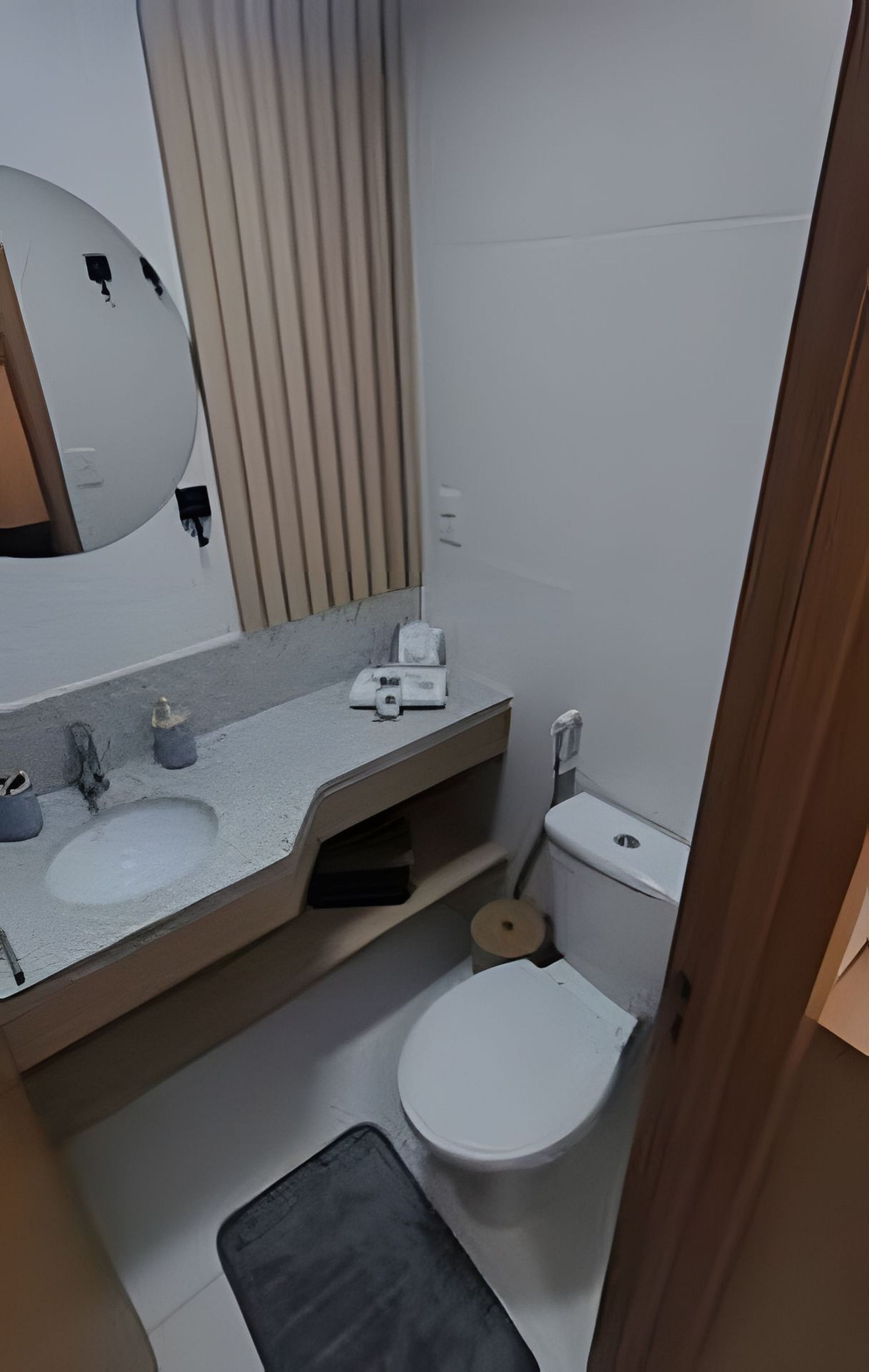 A small bathroom with a toilet, a sink, and a mirror.
