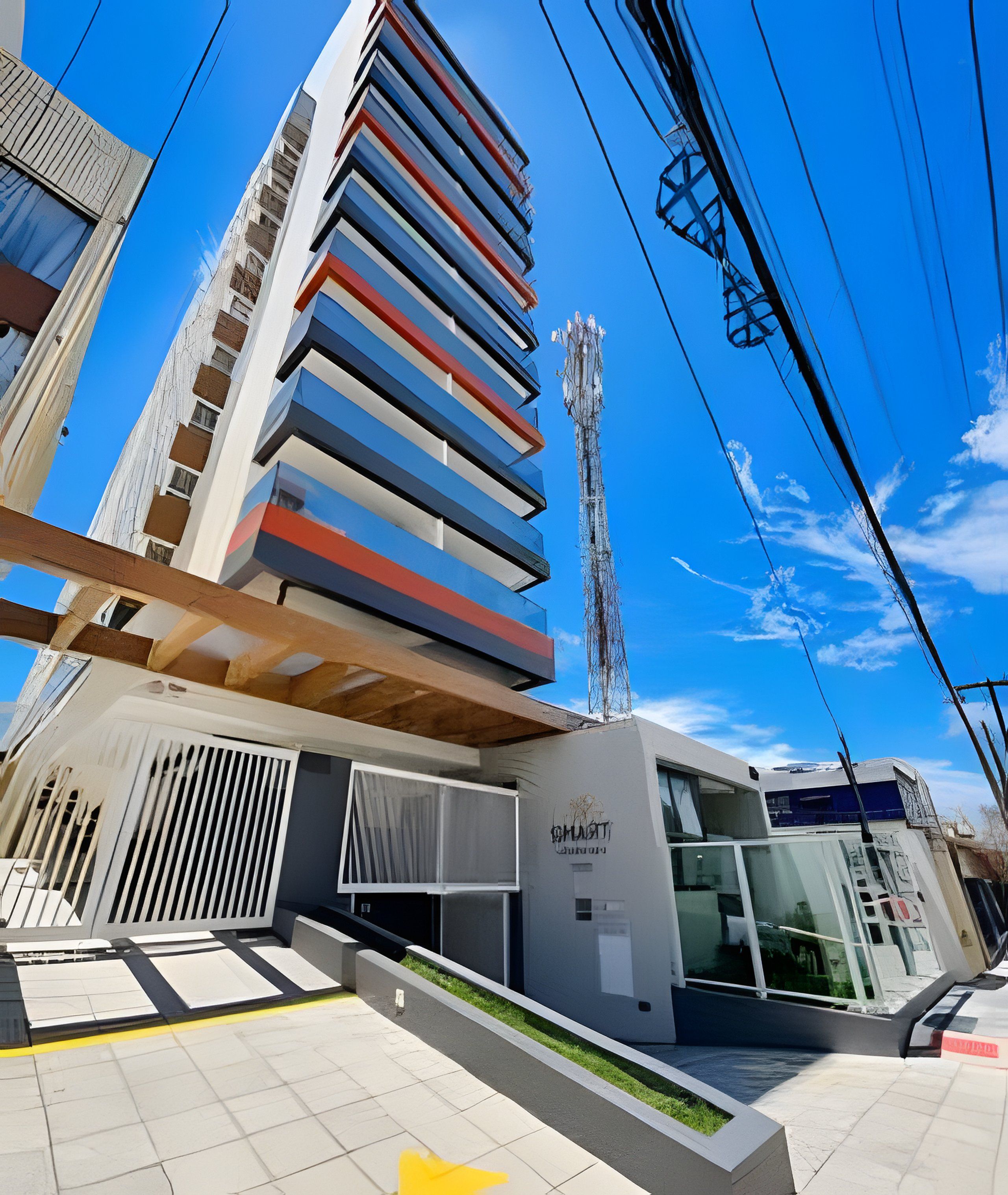 Um edifício moderno com fachada de vidro, antena visível e uma placa com a inscrição 'MUNAWIT'.