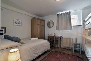 A bedroom with a bed, a chair, a desk, a radiator, a window with curtains, and a wall-mounted mirror. - Roz-Val - Appartement avec jardin proche de la mer (Pléneuf-Val-André)