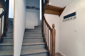 A staircase with a wooden handrail and carpeted steps leading to a door. - Roz-Val - Appartement avec jardin proche de la mer (Pléneuf-Val-André)