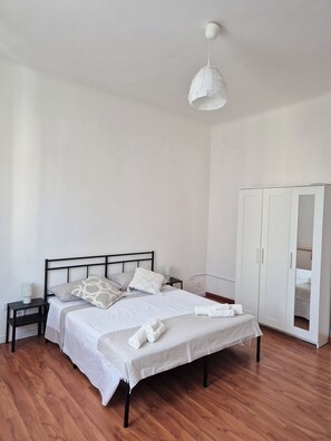 A bedroom with a bed, bedside tables, a wardrobe, and a hanging light fixture. - Cozy apartment 1 km from the train station and downtown (La Spezia)
