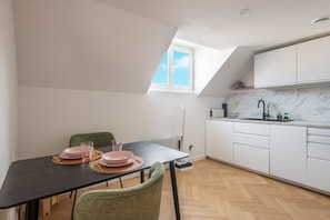 Eine moderne Küche mit weißen Schränken, einer Marmorarbeitsplatte und einem Essbereich mit Tisch für zwei Personen.