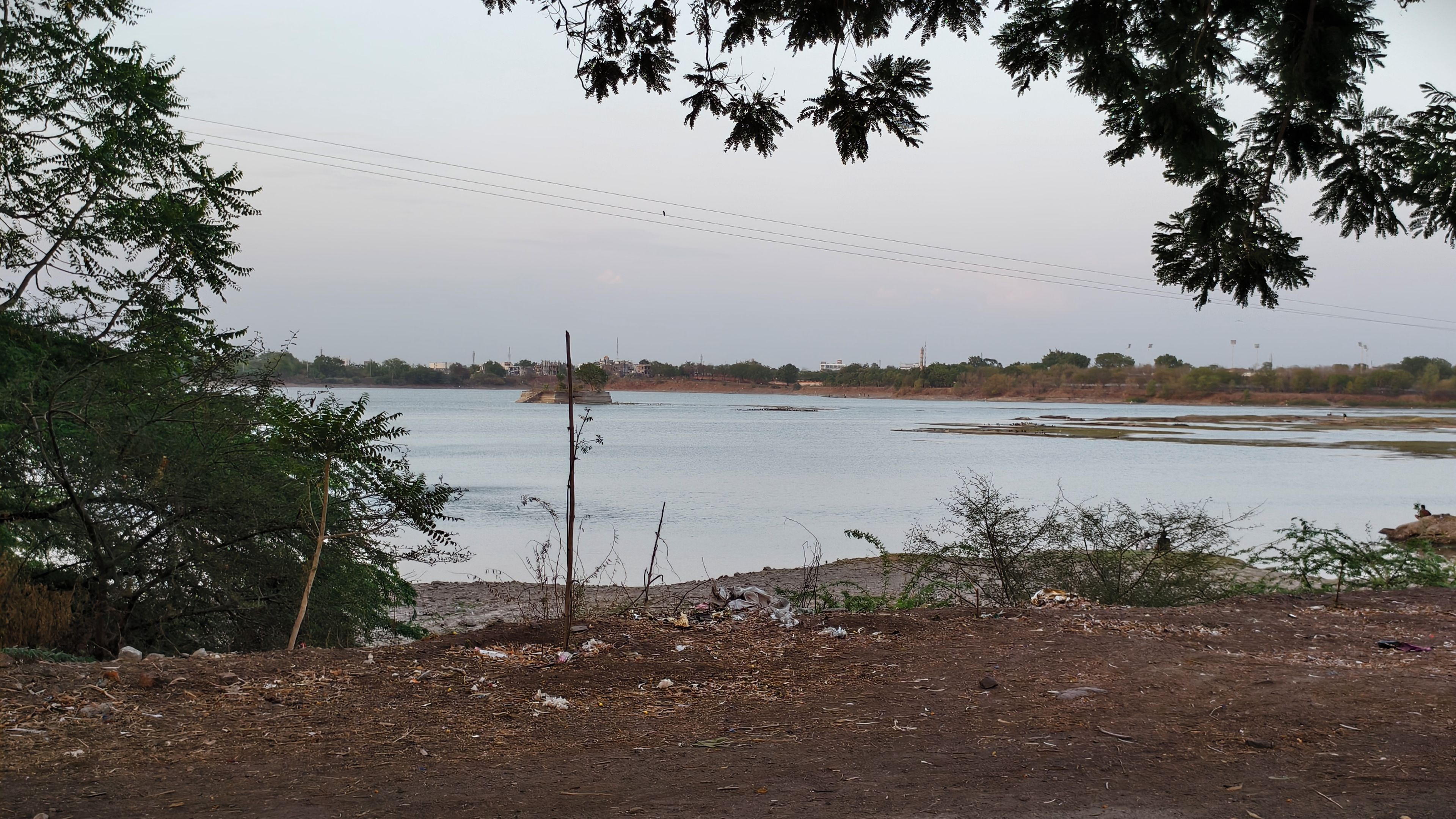 Un río con una orilla distante, rodeado de árboles y un cielo despejado.