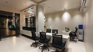 A modern hotel lobby with a reception desk, black office chairs, a water dispenser, and a view of the outside. - Shrikrushna The Lakeview Resort  (Jalgaon)