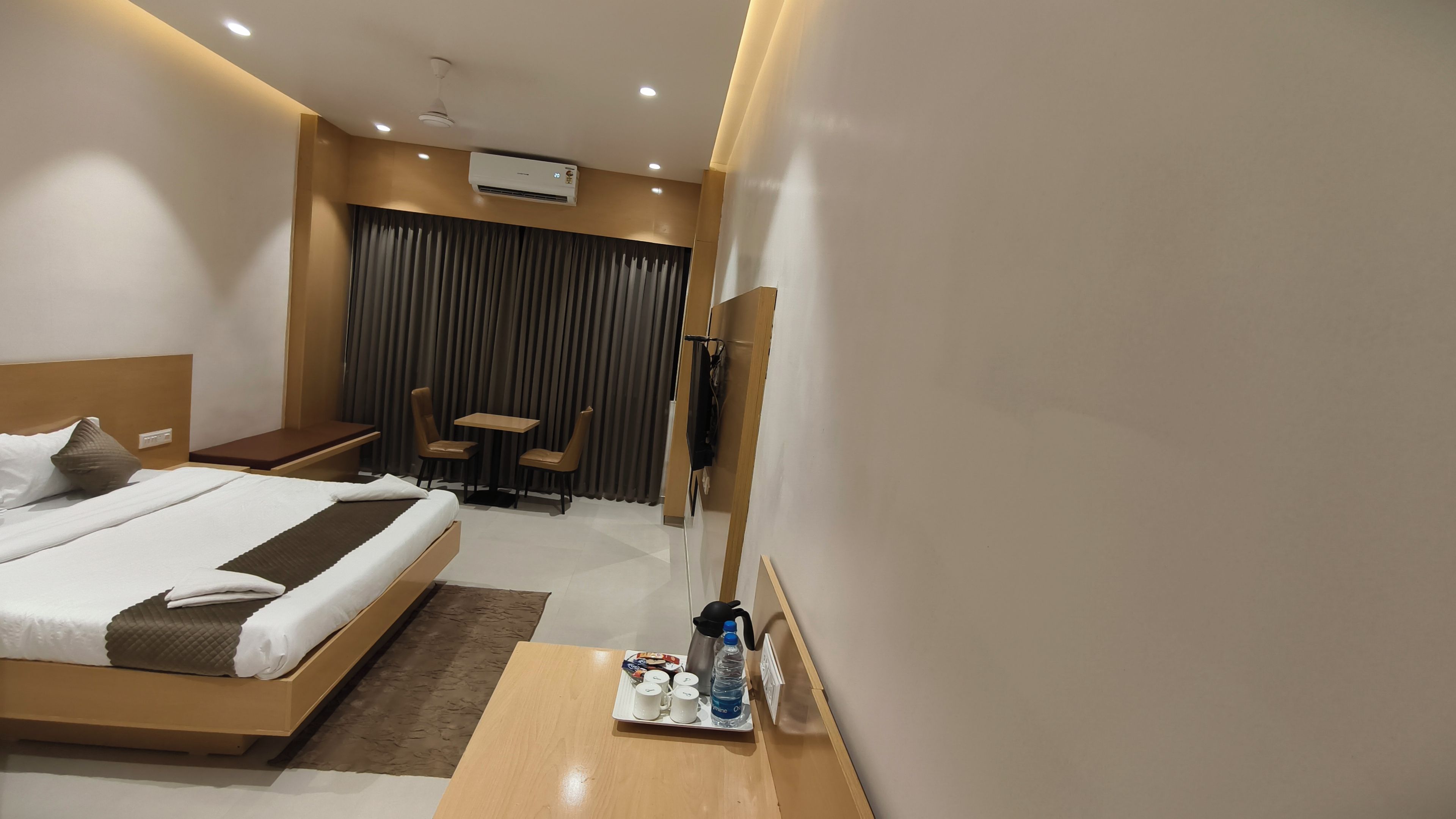 Ein Hotelzimmer mit einem Bett, einem kleinen Tisch mit Frühstücksgebäck, einer Sitzecke mit Tisch und Stühlen sowie einer Klimaanlage an der Wand.