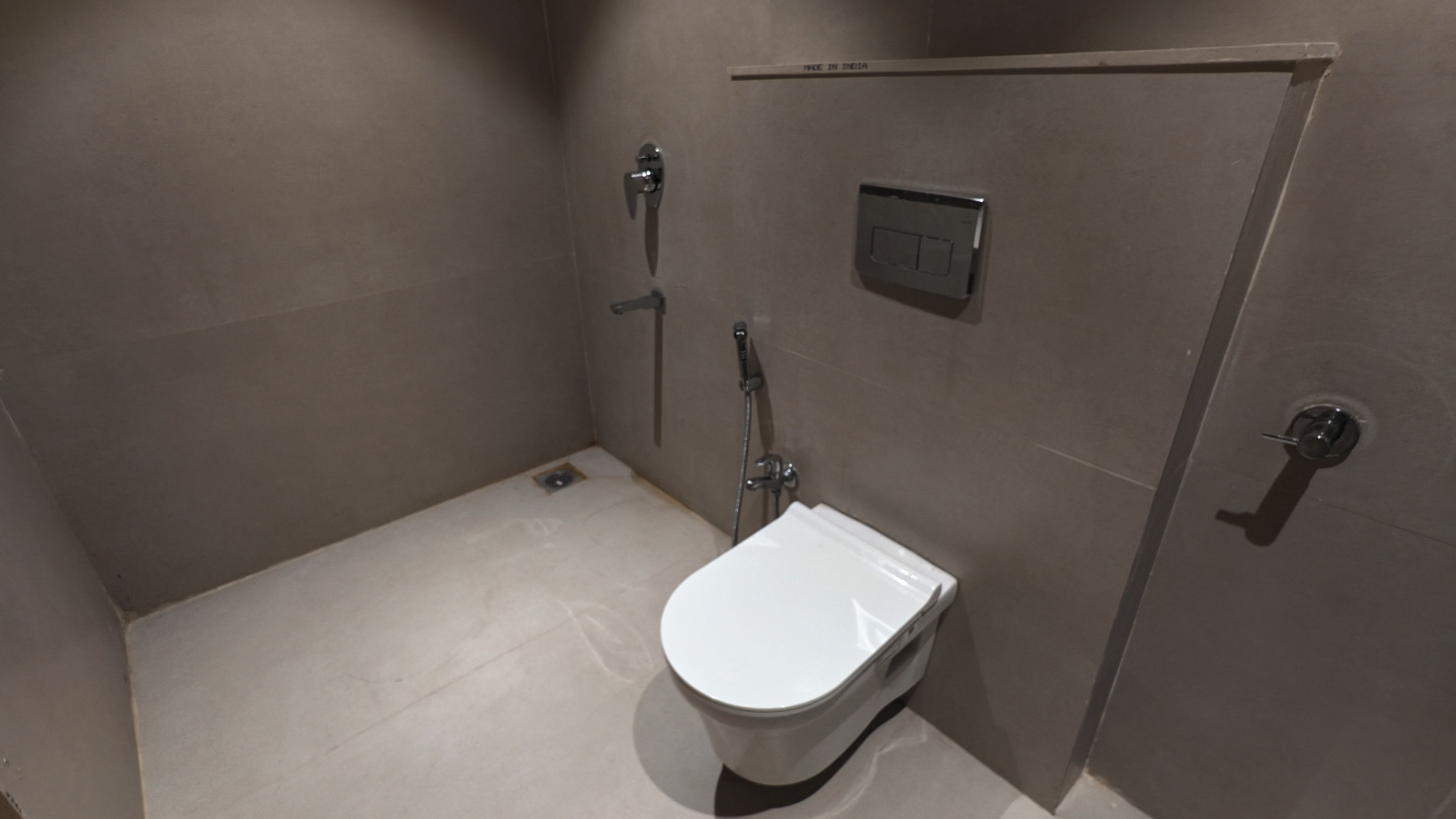 A small, enclosed bathroom with a toilet, a shower, and a hand dryer.