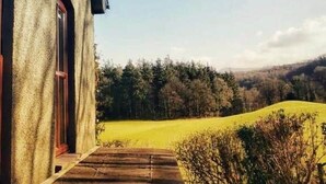 A building with a concrete exterior and a paved pathway leading to a grassy field. - The Escape, beautiful country estate cottage (Y Felinheli)