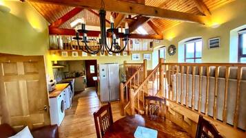 A spacious room with a wooden dining table, chairs, and a staircase leading to an upper level.