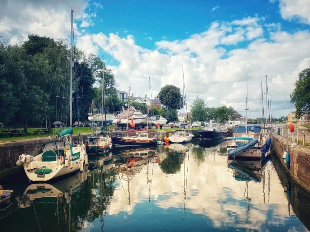 Ein Yachthafen mit vertäuten Booten, ein klarer Himmel und eine ruhige Wasseroberfläche.