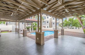 A covered outdoor area with a pool, tiled flooring, and a view of residential buildings. - Luxury High-end Modern Luxe Apartment (Johannesburg)