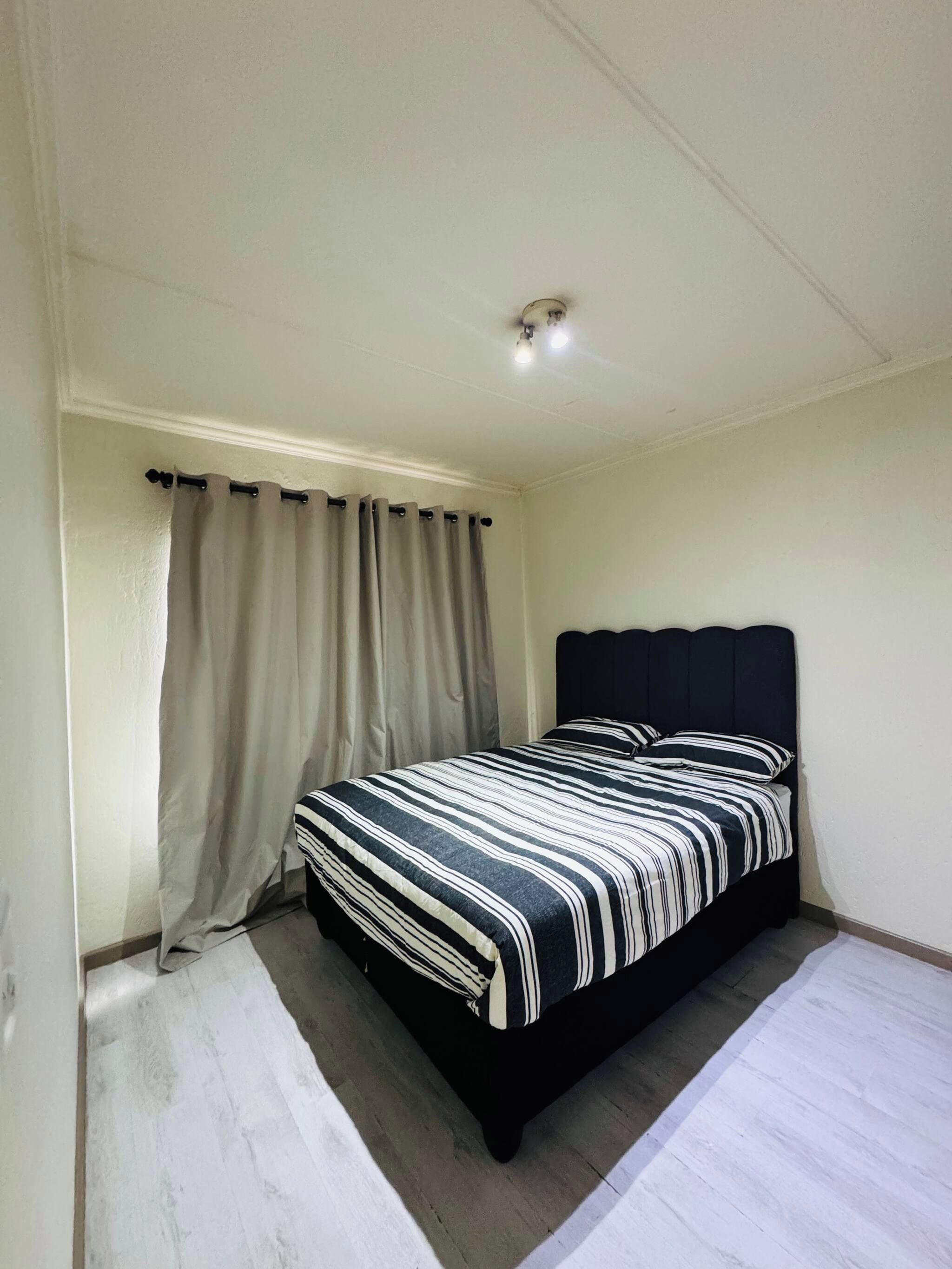 A bedroom with a bed, curtains, and a ceiling light.