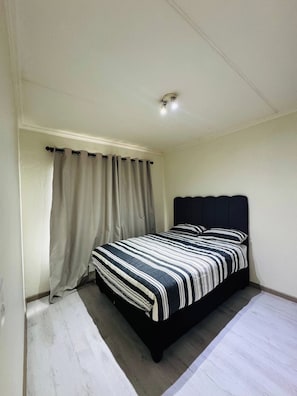 Ein Schlafzimmer mit Bett, Vorhängen und Deckenleuchte.