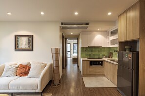 A modern kitchen with wooden cabinets, a built-in microwave, and a refrigerator. - Spacious 2-bedroom apartment in Hoan Kiem (Hà Nội)