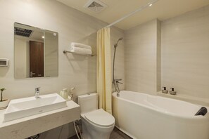A bathroom with a bathtub, toilet, sink, and a mirror. - Spacious 2-bedroom apartment in Hoan Kiem (Hà Nội)