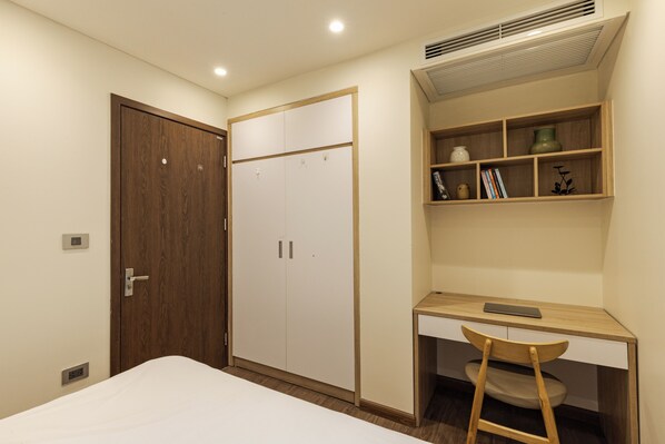 Una camera da letto con un letto, un armadio, una scrivania con sedia e uno scaffale con oggetti decorativi.