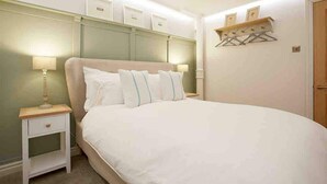 Une chambre avec un grand lit, des tables de chevet et une étagère murale avec des porte-manteaux.