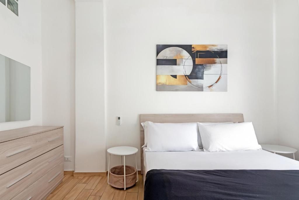 Un dormitorio moderno con cama, mesitas de noche, cómoda y una obra de arte en la pared.