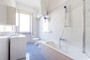 A modern bathroom with a bathtub, toilet, and sink. - Luciano Colosseo Apartment (Roma)