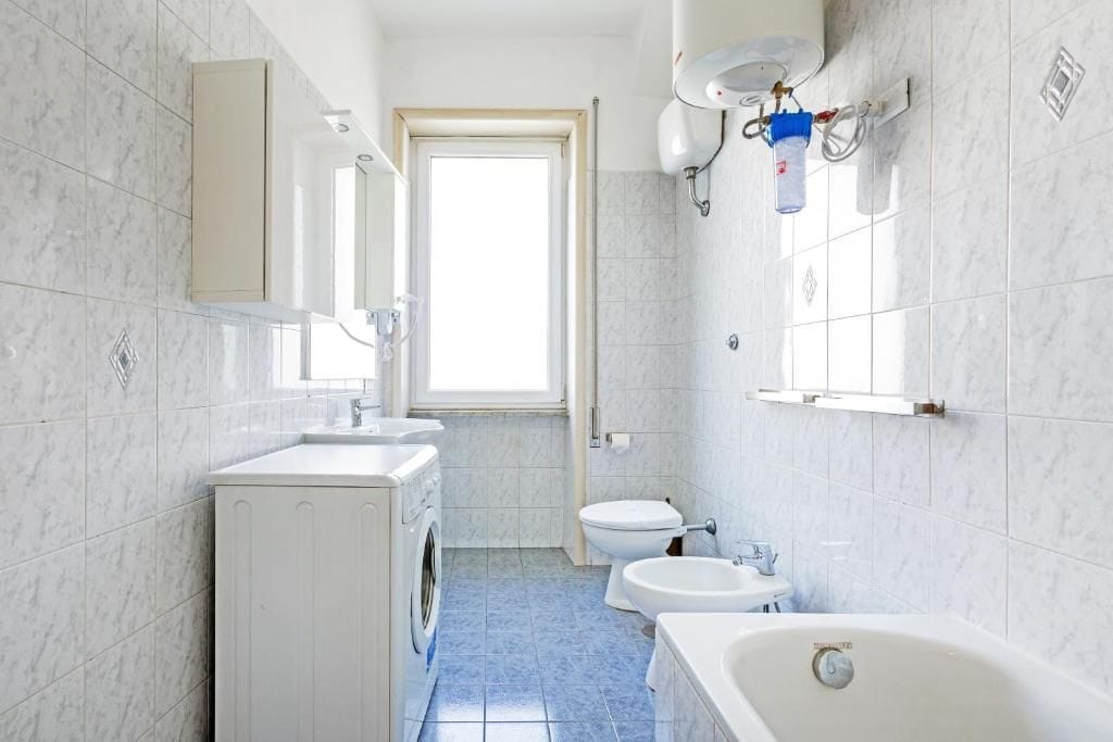 A bathroom with a washing machine, toilet, bidet, and bathtub.