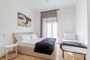 A modern bedroom with a bed, bedside table, and a small chair. - Luciano Colosseo Apartment (Roma)