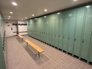 A row of green lockers with a bench in the middle, a caution sign on the wall, and a door with a sign above it. - True Ski-in Ski-out at Solitude - with pool and hot tub (Brighton)