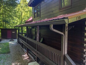 Une cabane en bois avec un porche, une porte rouge et le numéro « 170 » peint sur le côté.