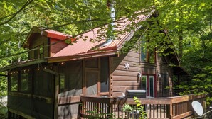 Une cabane dotée d’une terrasse, de grandes fenêtres et d’une cheminée.