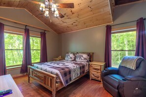 A wooden bedroom with a bed, a chair, and a nightstand. - Nantahala Adventures- Hot tub- Firepit- Foosball Table (Bryson City)
