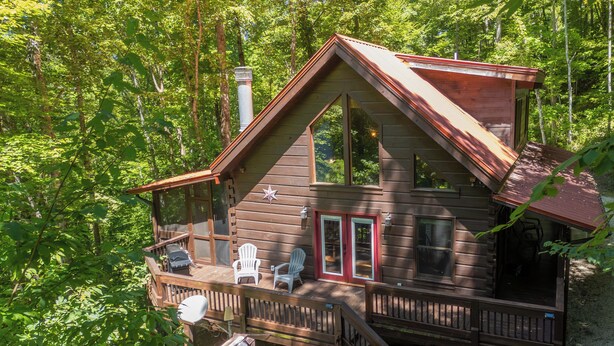 Une cabane dotée d’une terrasse, d’un bain à remous et de deux fauteuils Adirondack.