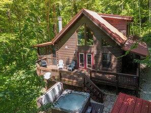 A cabin with a deck, hot tub, and two Adirondack chairs. - Nantahala Adventures- Hot tub- Firepit- Foosball Table (Bryson City)