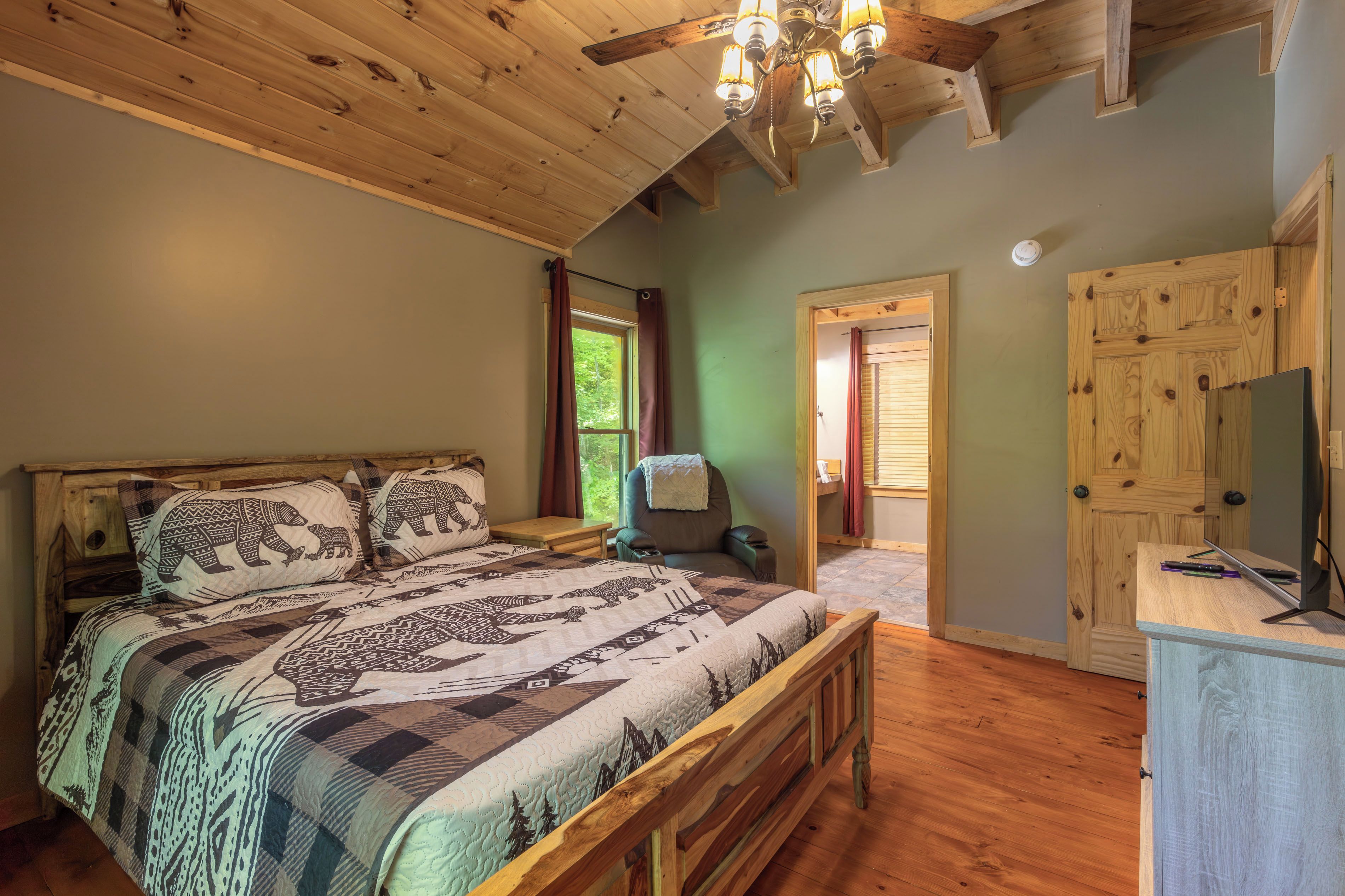 Une chambre à coucher avec un lit en bois, un bureau avec un ordinateur, une chaise et une armoire.