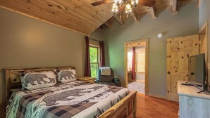 Une chambre à coucher avec un lit en bois, un bureau avec un ordinateur, une chaise et une armoire.