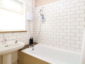 A bathroom with a white bathtub, a sink, and a shower with a handheld showerhead. - Leaf Lodge (Great Yarmouth)