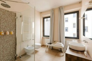 Ein modernes Badezimmer mit einer Duschkabine, einem Bidet, einer Toilette und einem Waschtisch mit großem Becken.